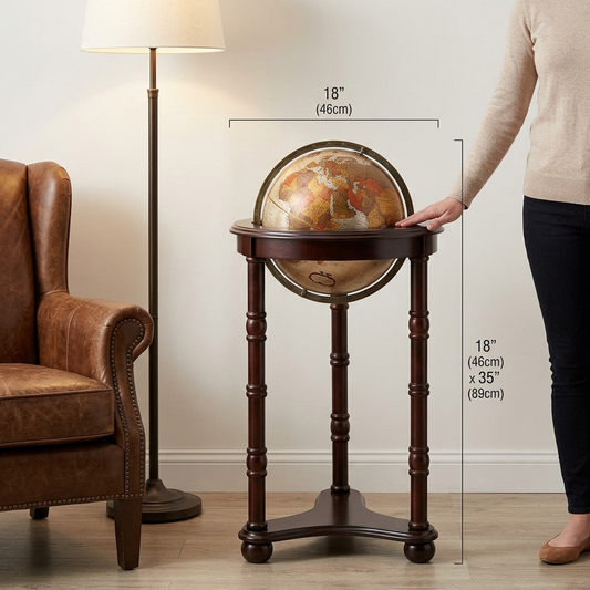 An e-commerce photo of the Replogle Lancaster Floor Globe, a bronze and wood piece, shown in a cozy living room beside a sofa for scale.