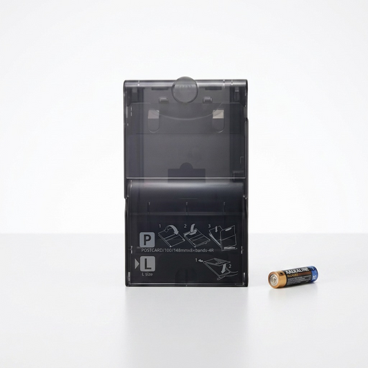 A photo of the Canon PCPL-CP400 paper cassette next to a standard AA battery.