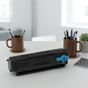 A 3D render of the Xerox toner cartridge with a blue handle placed next to common office supplies to demonstrate its size.