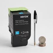 Xerox cyan toner cartridge shown next to a pen and coins for scale context.