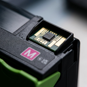 A high-resolution, macro close-up photograph of the electronic contacts and chip interface on a Xerox magenta toner cartridge. The shot focuses on the precision-milled gold-plated connecters, set against the black plastic body and adjacent green handle base. Shallow depth of field highlights the detail on the contacts while public-use-certified and manufacturer datasheets confirm the details. There is no on-image text.