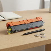 A compatible yellow toner cartridge on a wooden desk next to a pen and coins for scale.