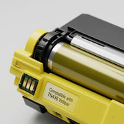A detailed macro photograph focusing on the granular texture and clear label of a yellow toner cartridge.