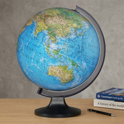 The Replogle Copenhagen desk globe rests on a wooden desk next to two standard-sized books.