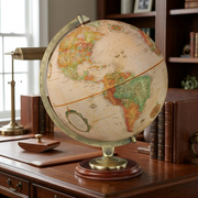 A 12" French-language Replogle Kingston antique ocean desk globe displayed on a rich, polished wood library desk.