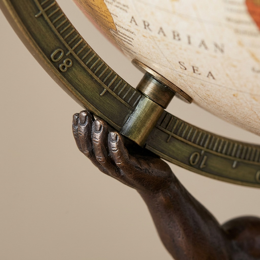 Extreme macro view: detailed bronze Atlas hand grips the matching metal meridian ring, showing fine texture and markings.
