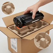 A pristine photo of an Elevate Imaging toner cartridge nestled securely within molded foam in a robust, unlabeled cardboard box, a hand lifting the protected product, conveying damage-free shipping.