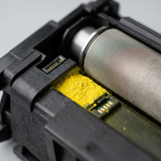 Extreme macro photo showing the fine mesh feed roller and a sample patch of yellow toner from the compatible HP CF402A cartridge, highlighting texture.