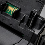 An extreme close-up photograph showcasing the complex molded texture, internal structure, and a key electrical contact point of the black toner cartridge.