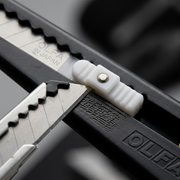 Macro detailed close-up showing the blade, handle texture, and slider of the Olfa 180 Metal Precision Knife.