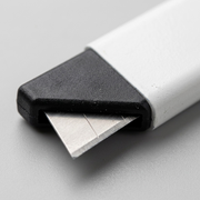 A macro photo of the Olfa CTN-1 carton cutter blade slot, emphasizing the sharp stainless steel edge.