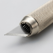 Macro view focusing on the knurled metal grip and precision art blade of the OLFA AK-1/5B.