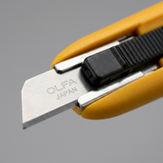 Extreme macro of Olfa SK-7 blade, textured slider, and 'OLFA JAPAN' etching.