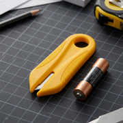 Scale reference photo: The yellow Olfa PK-2 utility knife on a dark mat next to a standard AA battery.