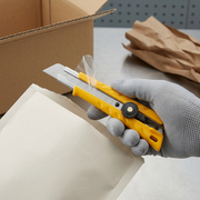 A visual matrix image showing the Olfa L-1 utility knife during unboxing from a protective padded mailer.