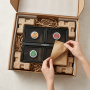 A realistic photo of the black mesh Keurig product rack being carefully unpacked from neutral protective shipping materials.