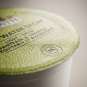 Macro photograph of the Van Houtte single serve K-Cup lid, focusing on the texture of the foil and the detail of the printed text.