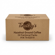 A high-resolution, centered view of the brown Timothy's Hazelnut Ground Coffee shipping box, featuring dark brown logo and text, against a pure white background.