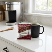 A realistic, detailed product-led image of the Keurig Orient Express coffee sachet placed in a lifestyle kitchen setting.