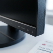 A close-up of the textured plastic bezel on a desktop monitor's lower right corner showing OSD icons.