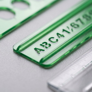 An extreme close-up photograph showcasing the precise die-cut details and material thickness of the purple lettering stencil.