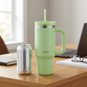 A lime-green Contigo 30 oz tumbler stands next to a standard 12 oz aluminum soda can on a wood desk.