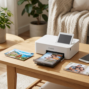 A white Canon SELPHY CP1500 printer is on a coffee table with family photos and a smartphone.