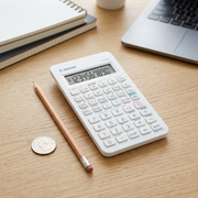 White Canon F-605G scientific calculator on a desk next to a pencil and a coin for scale.