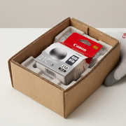 Unboxing a Canon PG-210 ink cartridge, protected by neutral brown paper and bubble wrap.