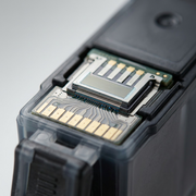 Macro photograph of the intricate integrated print head and gold electronic contacts on a Canon printer ink cartridge.