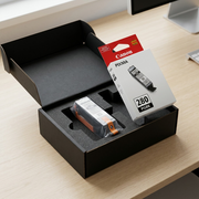 An open, padded shipping box contains a sealed, pristine Canon PGI-280 Black ink cartridge in its retail packaging, ready for installation.