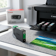 A Canon PGI-9 Green Ink Tank sits beside a professional photo printer, with a vibrant travel photo in the foreground.