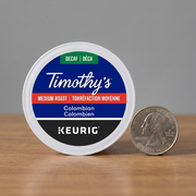 Scale Reference: A single Timothy's Decaf Colombian K-Cup is clearly sized against a US Quarter.