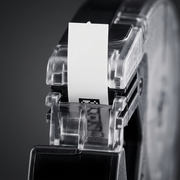 An extreme close-up view focusing on the clear label cassette tip, showing the precise path for the white plastic tape, the black printing mechanism section, and the complex injection-molded internal guide pins and texture of the robust black plastic body.