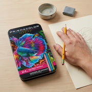 A scale reference image for Prismacolor Premier 24ct colored pencils, featuring the specific product tin next to an average-sized hand holding an standard pencil over a sketch.
