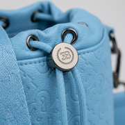Extreme macro close-up showcasing the engraved Bugatti emblem on a metal drawstring cord lock on a blue PU drift bag.