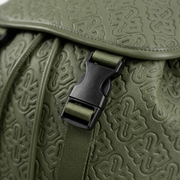 An extreme close-up photograph of the textured olive-green PU leather and metallic hardware on the Bugatti Rick Ross edition backpack flap.