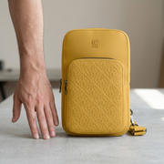 A vertical photo of the Bugatti Rick Ross sling bag next to a human hand for scale reference.
