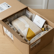 An open cardboard box revealing a carefully padded yellow sling bag, nestled for safe, protected delivery.