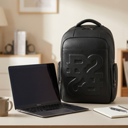 Scale reference photo: Bugatti Rick Ross embossed leather backpack next to a 13" laptop on a desk.