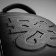 Extreme close-up of The Boss Edition backpack's textured black PU fabric and embossed logos.