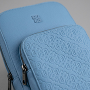 A detailed macro photograph showing the precise stitching and embossed "B" logo pattern texture on the Bugatti Rick Ross Blue Sling Bag's front panel, highlighting craftsmanship.