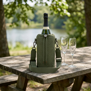 A lifestyle image showing the green champagne carrier on a stone table next to a bottle and glasses.