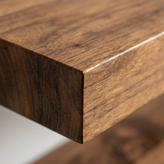 Macro close-up of solid medium walnut wood shelf corner, highlighting natural grain and fine finish.