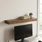 Lifestyle photo of the solid wood shelf above a desk, showing its size relative to a 27-inch monitor.