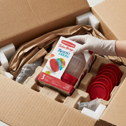 A premium close-up photo shows one intact Rubbermaid TakeAlongs 3-pack nested inside protective paper pulp in an open shipping box.