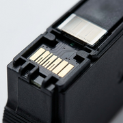 Macro inspection image of black ink cartridge, showing gold chip contacts and nozzle details