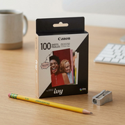 Scale reference photo for Canon ZINK 100-pack photo paper, shown next to a common pencil and sharpener for clear size understanding.