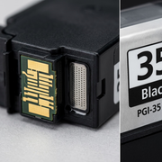A macro photograph focusing sharply on the metallic electrical contacts and ink nozzle interface of the PGI-35 black ink tank.