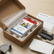 Photo of the Canon 7737A001 Ink & Paper Set, securely wrapped in protective bubble wrap and nested within a clean, sturdy corrugated brown cardboard shipping box, with an invoice visible.